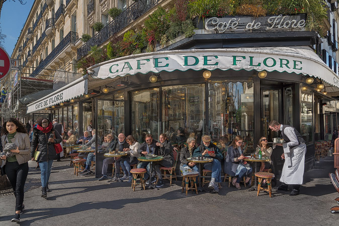 Des gens qui déjeunent et boivent du café, du vin et de la bière sur la terrasse du Café de Flore.
