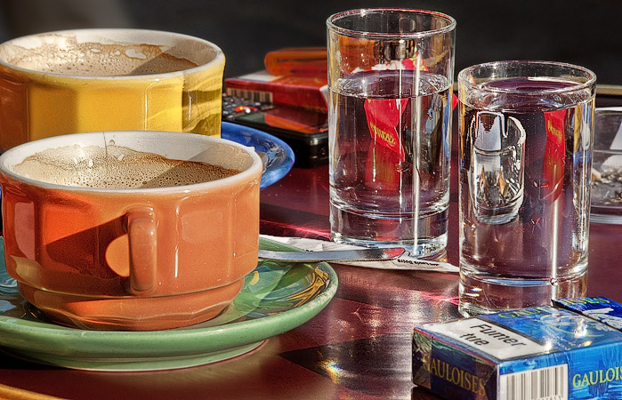 Deux tasses de café et deux verres d’eau sur une table d’un café parisien.