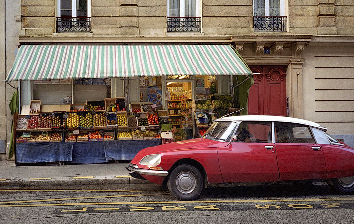 Une Citroën DS rouge devant une épicerie à côté de la place de la République.