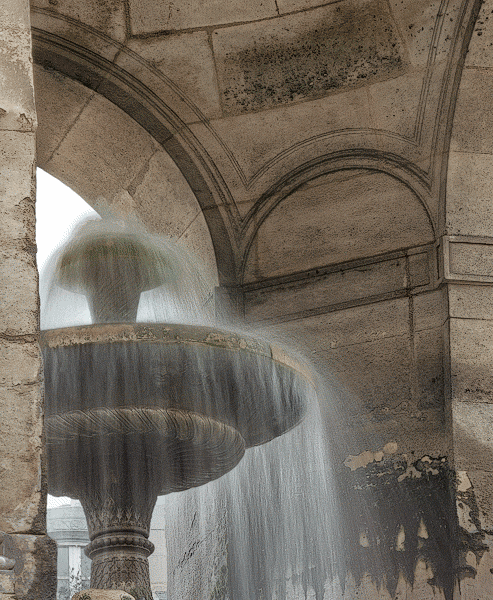 De l’eau giclant du bassin central dans la fontaine des Innocents dans la place Joachim-du-Bellay.