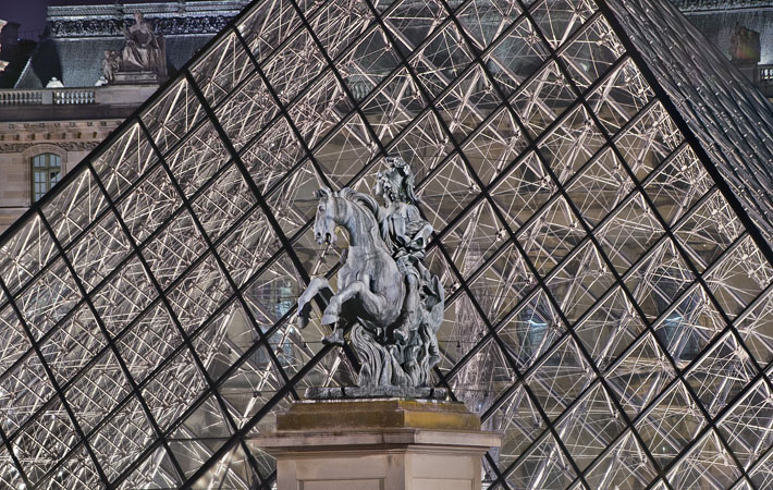 The sculpture of Louis the 14th in courtyard of the Louvre Museum at night.