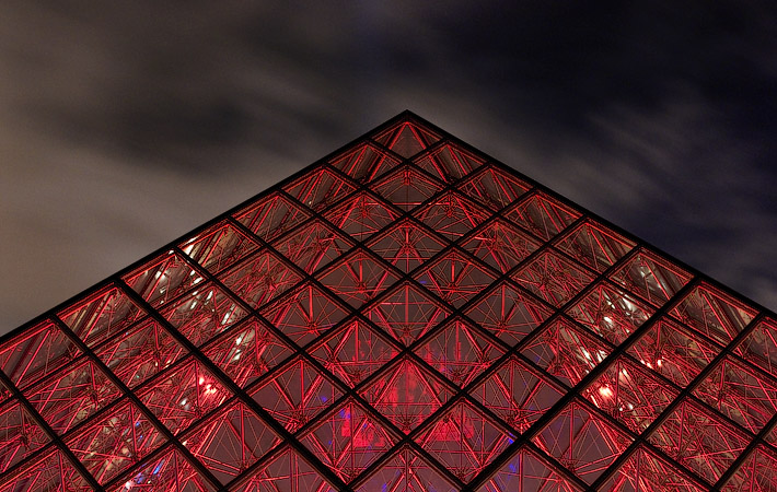La Grande Pyramide du Louvre illuminée en rouge le soir.