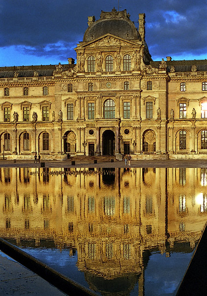 Pavillon Sully du Louvre reflété dans des bassins au coucher de soleil..