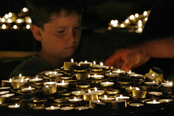 A boy with prayer candles inside Notre-Dame.