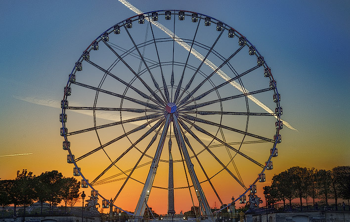 The sun setting behind a Ferris wheel the western edge of the Tuileries Gardens