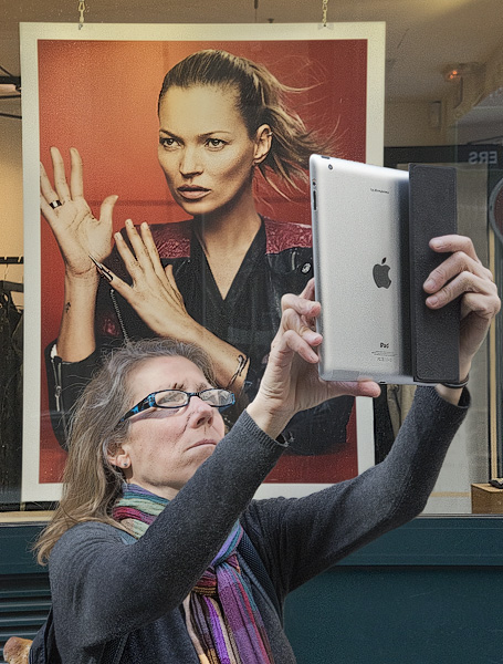 A woman taking a picture with an Apple iPad on rue des Rosiers.