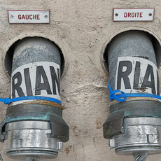 Des étiquettes au-dessus des colonnes sèche indiquant quelle est sur la gauche et quelle est sur la droite sur la rue Tournefort.