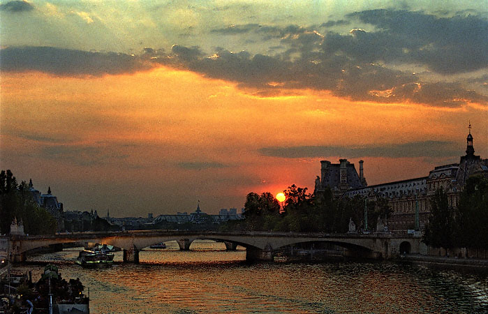 Un coucher du soleil sur le pont du Carrousel, le Grand Palais et le musée du Louvre.