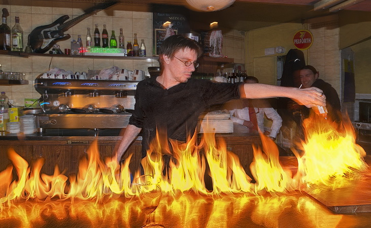 Le barman du café “The Station” en train d’asperger le zinc avec du liquide Zippo en flammes.