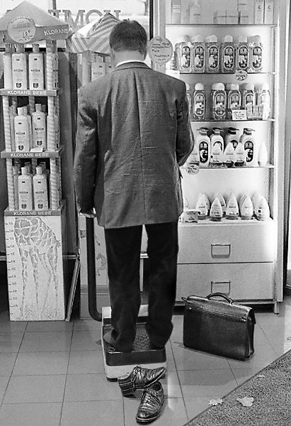 A man weighing himself in a pharmacy on boulevard Sébastopol.