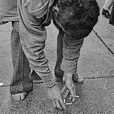 Un homme sans domicile fixe jouant avec des mégots de cigarettes à Times Square, New-York.