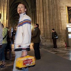 A man inside Notre-Dame with a ten-pack of cheap beer.