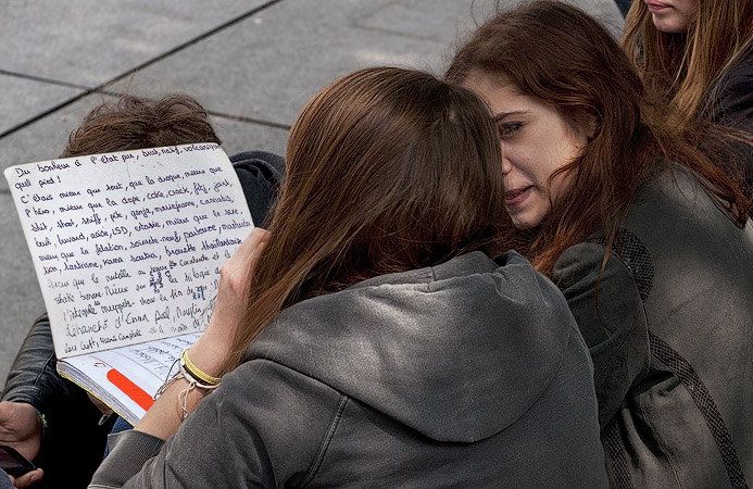 A teenaged girl writing about sex and drugs in her notebook near the Pompidou Center.
