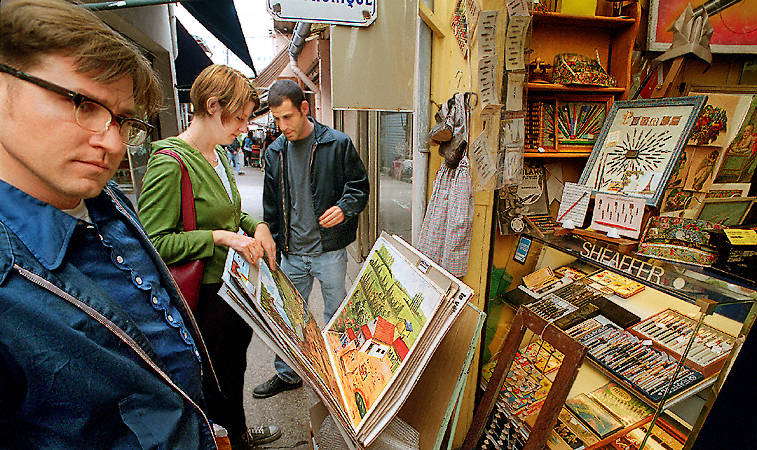 Thre people looking at posters and collector pens at the Saint-Ouen Flea Markets.