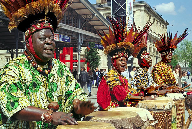 Quatre hommes en train de jouer des tambours africains au parc de la Villette.