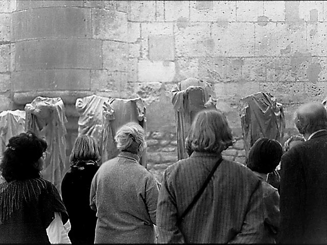 Des visiteurs au musée du Moyen Âge regardant des statues décapitées.