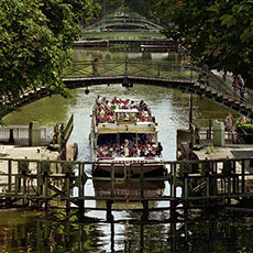 A tourism boat going under a footbridge over canal Saint-Martin.