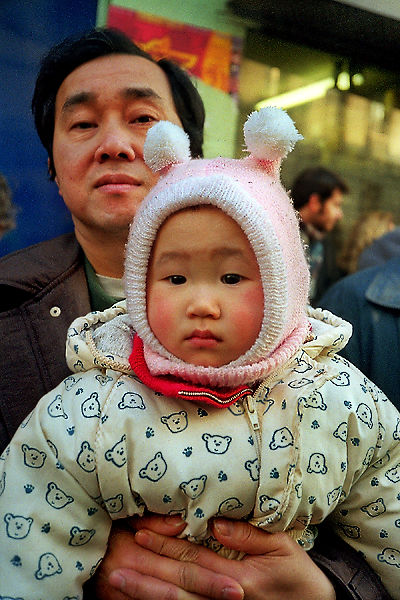 Un homme avec sa fille en train de regarder le défilé du nouvel an chinois sur la rue de Belleville.