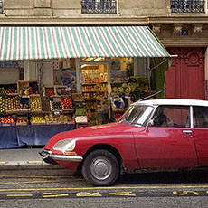 Une Citroën DS rouge devant une épicerie à côté de la place de la République.