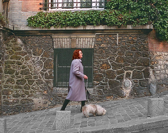 A woman walking uphill with her dog in Montmartre.