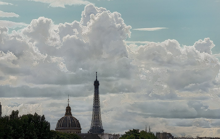 The Eiffel Tower and l’Institut de France in front of majestic clouds.