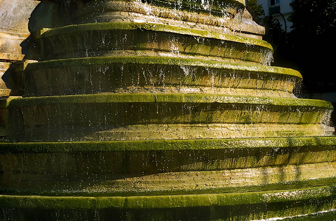 Des vasques de la fontaine Innocents couvertes de mousse en été.