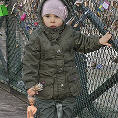 A little girl holding a Barbie doll by the hair on pont des Arts.