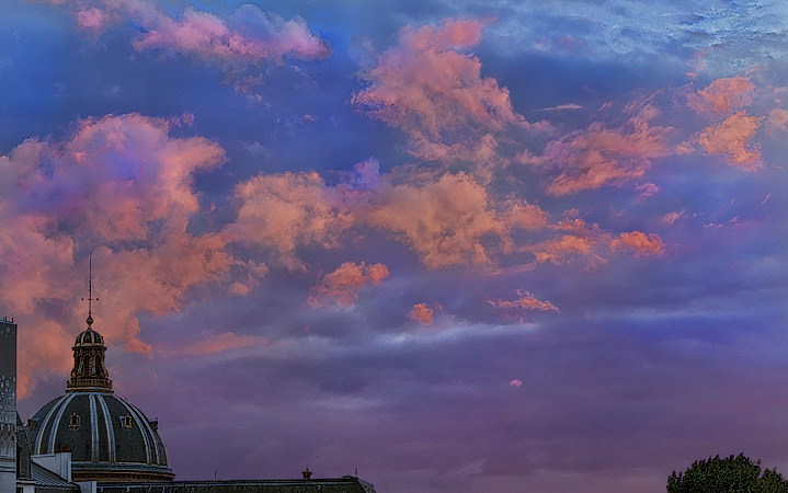 Orange clouds floating above l’Institut de France at sunset.