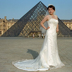 Une jeune mariée en tenu de mariage devant la Pyramide du musée du Louvre.