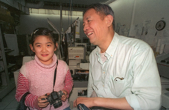A young girl with a Nikon F3 and her father in their photofinishing lab in Belleville.