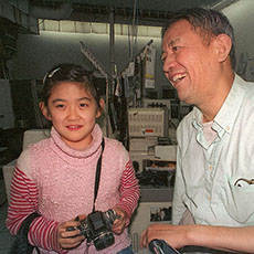 A young girl with a Nikon F3 and her father in their photofinishing lab on rue de Belleville.