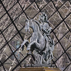 The sculpture of Louis the 14th in courtyard of the Louvre Museum at night.