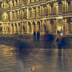 People walking through the Louvre Museum’s cour Carrée at night.