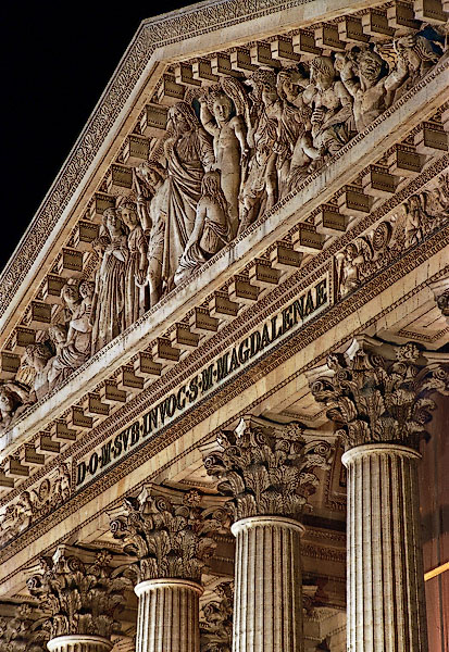 The upper portion of la Madeleine’s façade at night.