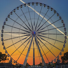 Le soleil se couche derrière une grande roue au bord occidentale du jardin des Tuileries.