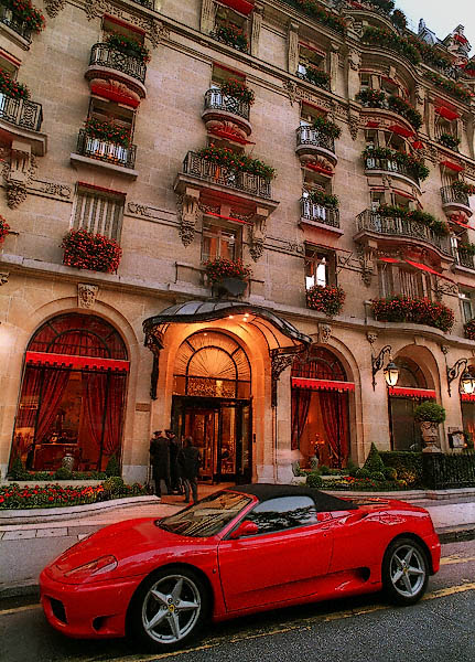 Une Porsche rouge devant l’entrée principale de l’Hôtel Plaza Athénée sur l’avenue Montaigne.