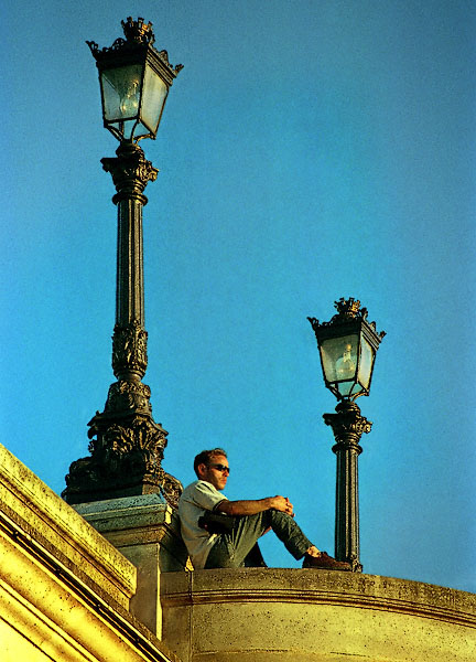 A young man watching the sun set over the River Seine from pont Neuf.
