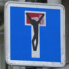 Un panneau impasse avec un graffiti noir de la figure de Jésus-Christ crucifié plaquée dessus sur la rue Aubry-le-Boucher.