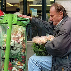 Un homme devant une poubelle dans la place de la République en train de préparer des roses pour les vendre.