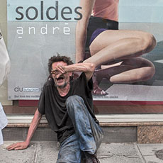 A homeless man sitting in front of advertising for the «André» clothing shop on rue Saint-Antoine.