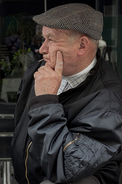 Un homme d’un certain âgé avec une allumette dans la bouche sur la rue de la Verrerie.