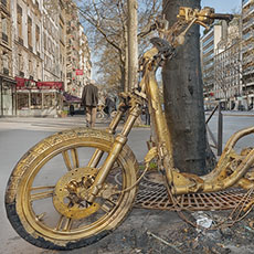 A dismantled and burned scooter spraypainted gold on boulevard du Montparnasse.