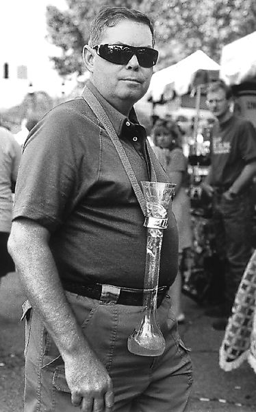 A man with glass beer container hung from his neck by a canvas strap in Kentucky.