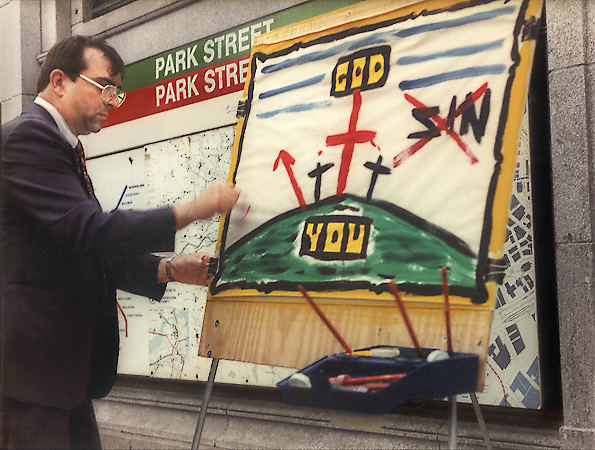 A evangelist preaching his message with finger painting next to the Park Street MBTA station in Boston.