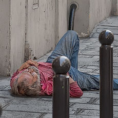A homeless man sleeping on the sidewalk on rue Saint-André-des-Arts.