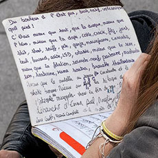A teenaged girl writing about sex and drugs in her notebook near the Pompidou Center.
